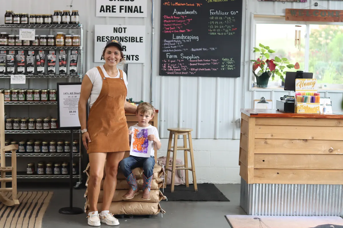 A woman and child beside the counter inside a garden-center shop.
